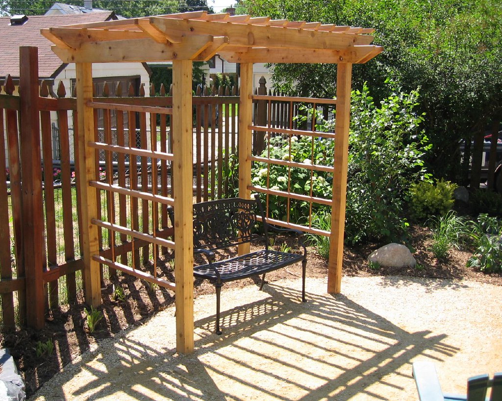 Timber garden arbor with a bench seat surrounded by planting