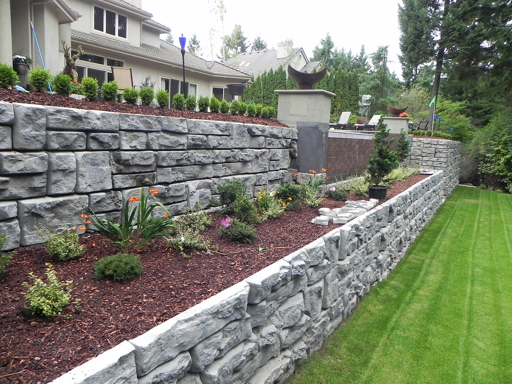 Stacked stone retaining wall with garden bed and lawn